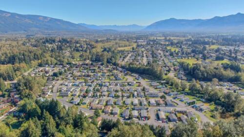 An aerial view of a residential area with trees and mountains.